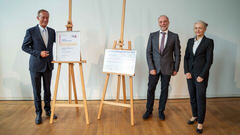 Staatsminister Axel Wintermeyer (links) ehrt Sabine Jost-Schmitt und Dr. Stefan Tron vom Projekt „Honigbienen, Wildbienen und Blühstreifen“.