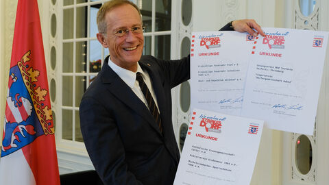 Chef der Staatskanzlei mit Urkunden zur Auszeichnung "Starkes Dorf"