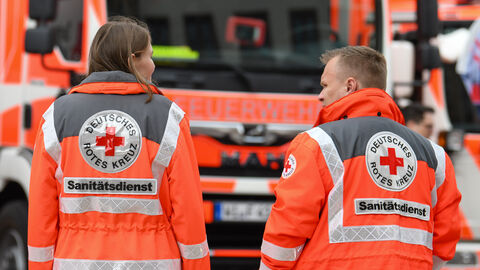 Sanitäter und Sanitäterin vor Feuerwehrauto