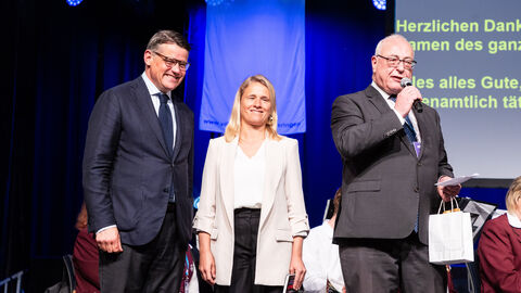 Drei Personen auf einer Bühne.