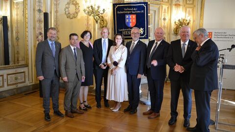 Mehrere Männer und zwei Frauen stehen zusammen und lächeln in Kamera.