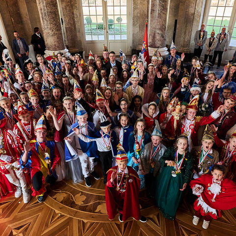39 Kinderprinzenpaare stehen jubelnd in einem Saal, in ihrer Mitte der hessische Ministerpräsident.